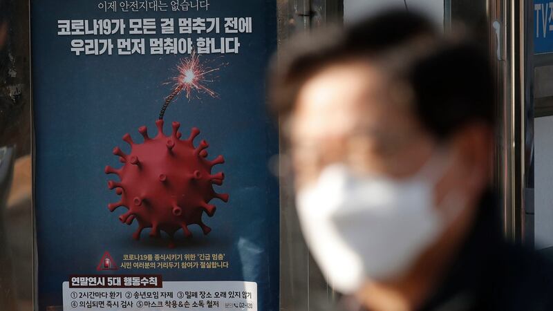 A man wearing face mask as a precaution against the coronavirus walks near a poster emphasising an enhanced social distancing campaign in Seoul, South Korea, on Saturday. The signs read: ‘We have to stop before Covid-19 stops everything.’ Photograph:  Lee Jin-man