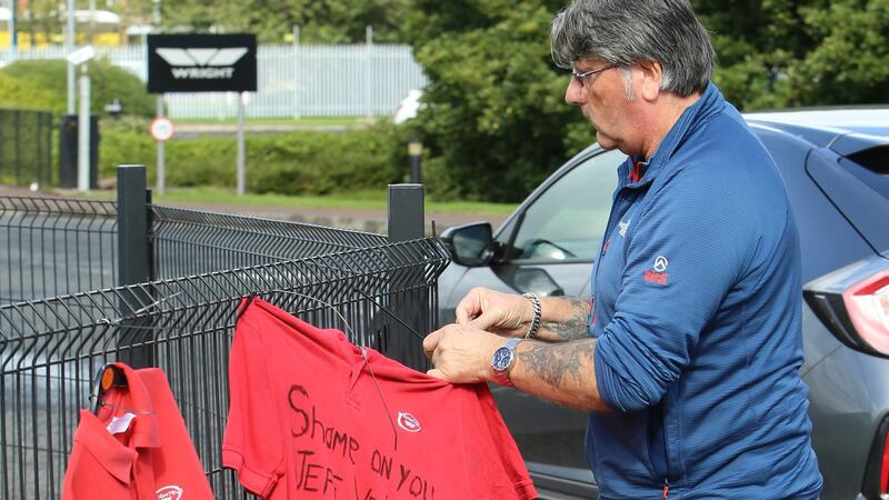 A former Wrightbus employee puts up a T-shirt with the words ‘Shame on you Jeff Wright’ outside the factory in Co Antrim. Photograph:  Paul McErlane