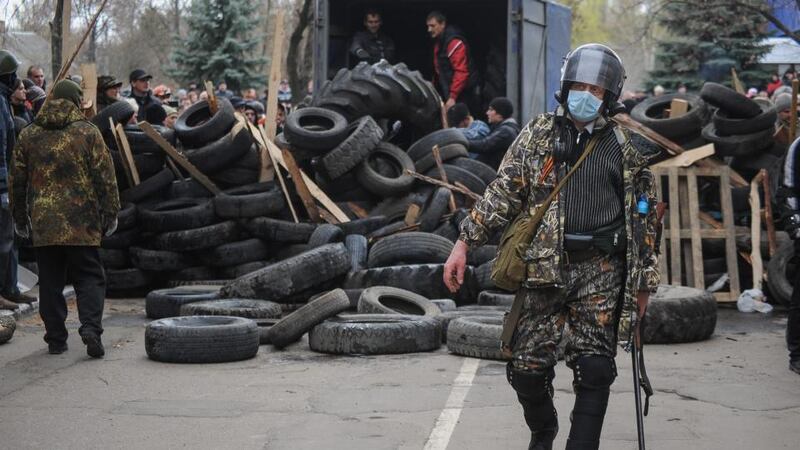 Armed men in front of the seized police headquarters in Slaviansk, Ukraine, today, with protesters preparing to build barricades made of tyres in the background. Photograph: Roman Pilipey/EPA