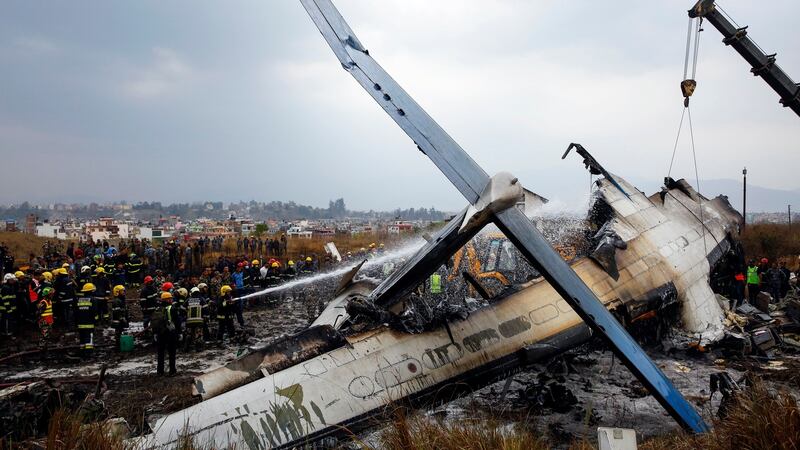 Firefighters work on the burning wreckage of US-Bangla Airlines Flight 211 while a crane is used amid ongoing rescue efforts  at  Tribhuvan International Airport in Kathmandu, Nepal, on Monday. Photograph: Narendra Shrestha/EPA