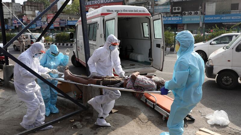 Indian health workers wearing Personal Protective Equipment (PPE) carry an unidentified man who was lying unconscious on the ground  in New Delhi, India. Photograph: Rajat Gupta/ EPA