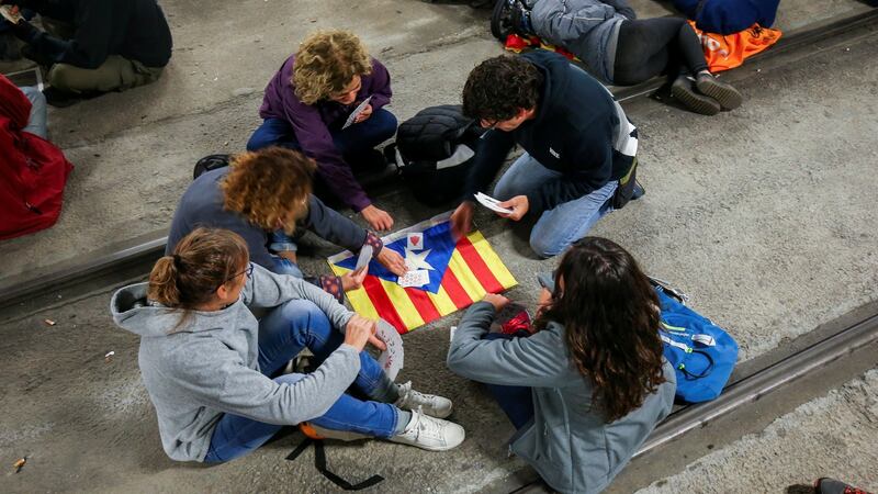 Protesters play cards on top of a Catalan separatist flag while blocking the tracks inside the station of the high speed train AVE during a partial regional strike in Girona, Spain. Photograph: Albert Gea/Reuters