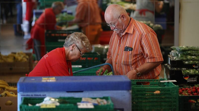 A volunteer guides Wolfgang, who said he is a retired construction engineer who fell on hard times after a business venture went sour, to choose groceries at the food distribution point. Sean Gallup/Getty Images