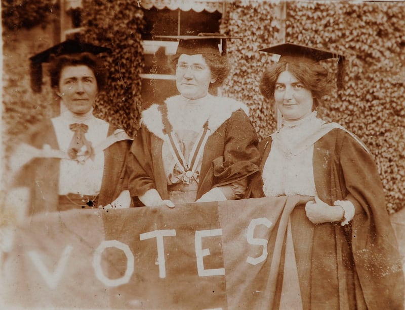 Hanna Sheehy-Skeffington, Kathleen Shannon and Kate Sheedy, in their graduation robes and mortar-boards, carrying a banner saying "Votes" (for women)
Photograph: The National Library