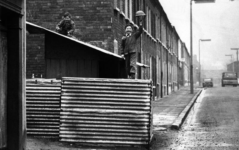 Boys play in an abandoned British army post north of the peace line separating Catholic and Protestant areas in Belfast in 1972. Photograph: Oliver Morris/Getty