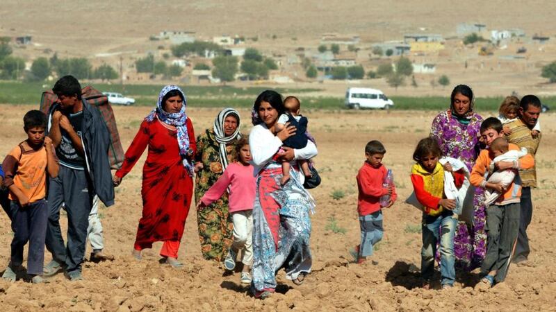 Turkish police and soldiers observe Syrian Kurds waiting   to cross into Turkey near the southeastern town of Suruc in Sanliurfa province yesterday. Photograph: Reuters