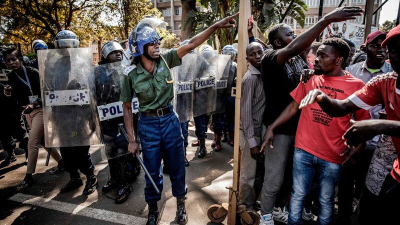 Riot police officers close the entrance to the building in Harare where Zimbabwe’s election results are being annunced, as supporters of the opposition Movement for Democratic Change party protest   on Wednesday against alleged vote rigging. Photograph: Luis Tato/AFP/Getty Images