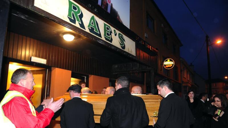 People clap as the body of Jackie Healy-Rae is carried into his pub in Kilgarvan in Co Kerry  surrounded by his close family. Photograph: Don MacMonagle