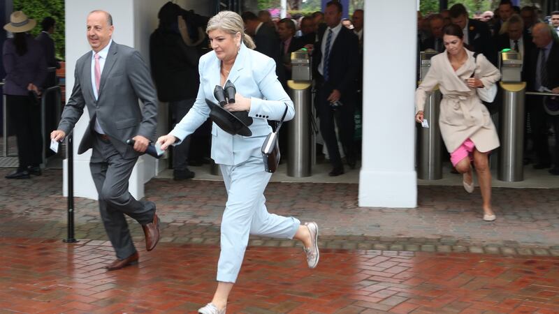 Racegoers run through the gates after delays to trains from the city due to the rain. Photo: Dave Crosling/EPA