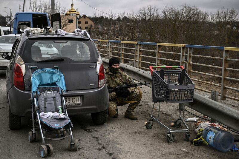 A Ukrainian serviceman takes cover behind a car in the city of Irpin, northwest of Kyiv on March 15th. Photograph: Aris Messinis/AFP via Getty Images