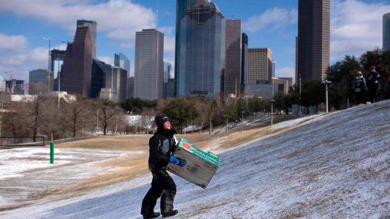 A boy walks up a snow covered hill after sledding down it in a box in Houston, Texas. Photograph: Mark Felix/AFP via Getty Images