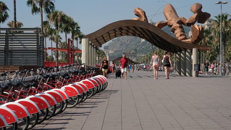 People walk under a sculpture by Spanish artist Javier Mariscal titled ‘Giant lobster’ near a bicycles for hire station by the marina in Port Vell on July 12, 2017 in Barcelona, Spain. Port Vell or ‘Old Harbor’ is a waterfront harbor and part of the Port of Barcelona. It was built as part of an urban renewal program prior to the 1992 Barcelona Olympics. Before this, it was a run-down area of empty warehouses, railroad yards, and factories. Photograph:  Kaveh Kazemi/Getty Images