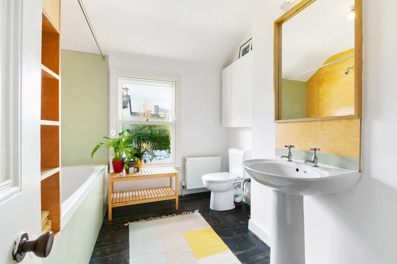 In the bathroom, the bath doubles as a shower with a showerhead attached to the wall.