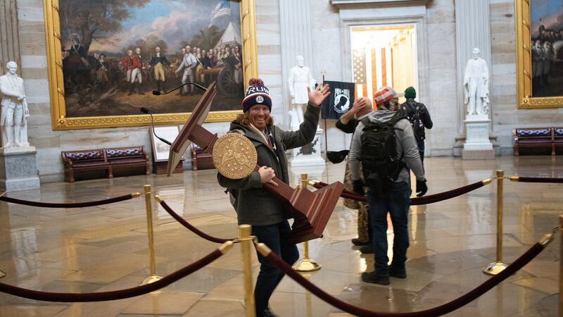 A pro-Trump protester carries the lectern of US Speaker of the House Nancy Pelosi through the Rotunda of the US Capitol Building after a pro-Trump mob stormed the building in Washington, DC. Photograph: Win McNamee/Getty Images