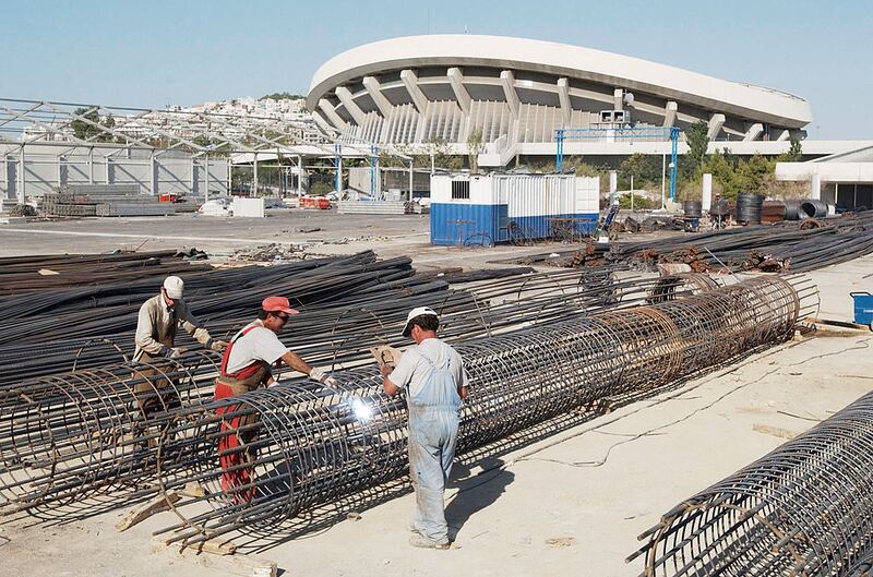 Workers work on bridge supports near a basketball stadium in Piraeus, the port of Athens, Greece, ahead of the 2004 Olympics. Photograph: Chris Hondros/Getty Images