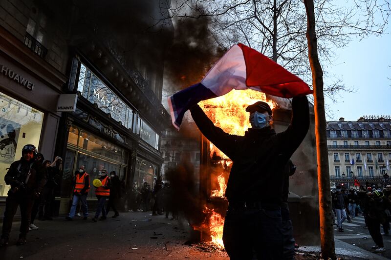 A protester holds a French flag next to a burning news kiosk. Photograph: Alain Jocard/Getty Images