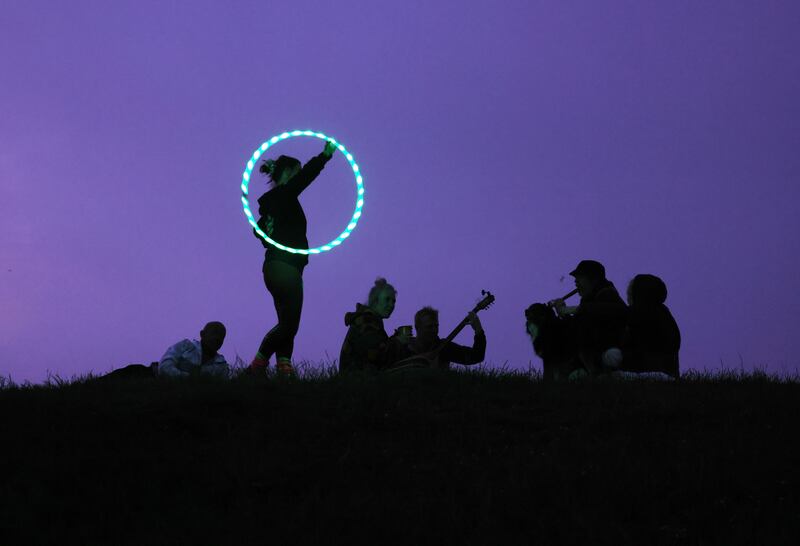 Ashlinn Molloy from Dún Laoghaire brandishes a circle of light with a group of musicians as sunrise nears on June 21st at Tara. Photograph: Alan Betson/The Irish Times