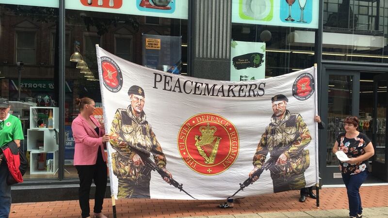 Up to 40 loyalists held a counterprotest on Royal Avenue against the backdrop of a large UDR-themed banner emblazoned with the words “Peacemakers”.