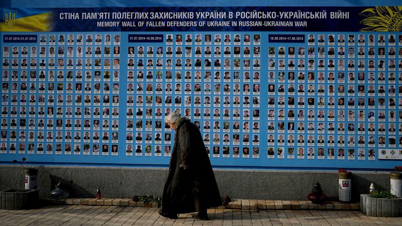 A woman walks past the Memorial Wall of Fallen Defenders of Ukraine  in Kyiv. Photograph: Natacha Pisarenko/AP Photo