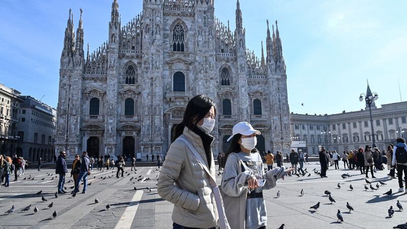 Two women wearing a protective facemask walk across the Piazza del Duomo, in front of the Duomo, in central Milan on Monday. Photograph: Andreas Solaro/AFP via Getty Images
