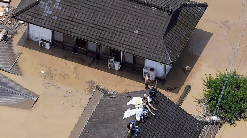 Residents are stranded on the rooftop of a house submerged in muddy waters that gushed out from the Kuma River in Hitoyoshi, Kumamoto prefecture, southwestern Japan. Photograph: Kyodo News via AP