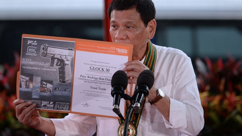 Philippine president Rodrigo Duterte holds up a certificate showing a Glock 30 handgun, awarded to him by a Philippine firearms importer for his fight against illegal drugs, during a “talk to the troops”  in Manila on Tuesday. Photograph: Ted Aljibe/AFP/Getty Images