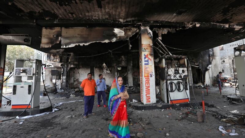 People stand at a damaged fuel station in New Delhi, India after it was set on fire by a mob during clashes  between people demonstrating for and against a new citizenship law. Photograph: Rupak De Chowdhuri/Reuters