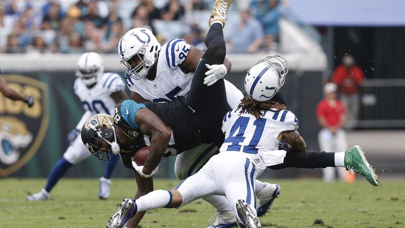 Tight End Marcedes Lewis of the Jacksonville Jaguars is tackled by defensive tackle Johnathan Hankins and safety Matthias Farley, who loses his helmet. Photo: Don Juan Moore/Getty Images