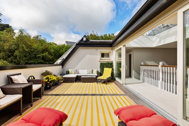 Stairs at the side of Woodridge’s front hall lead to a wide landing with a balcony overlooking the hall; opposite are sliding double-glazed doors opening onto the wide decked terrace looking over the back garden.