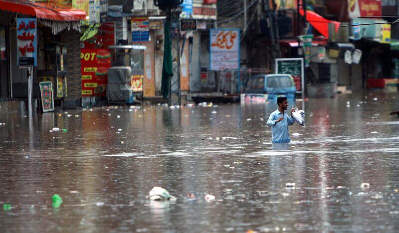 A man makes his way through a flooded area after heavy monsoon rains in Rawalpindi, Pakistan. Photograph: Sohail Shahzad
