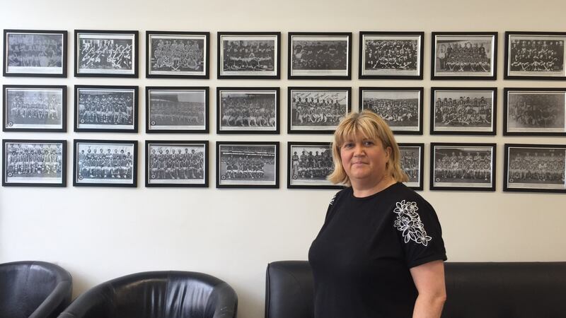 Deidre O’Reilly in front of the photo wall of   Kilkenny hurling teams inside her barber shop. Photograph: Sarah Mooney