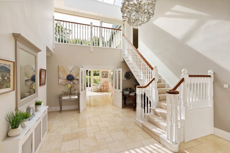 The double-height entrance hall, floored with polished Travertine tiles, is very bright, with light flooding down from a large rooflight. 