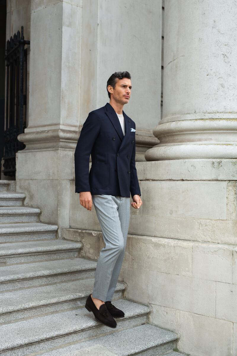 Isaia birds-eye sports jacket in navy, €3,195; slim fit Thomas Mason white top, €159; Richard J Brown luxury cashmere grey trousers, €499; loafers, €369. From Louis Copeland