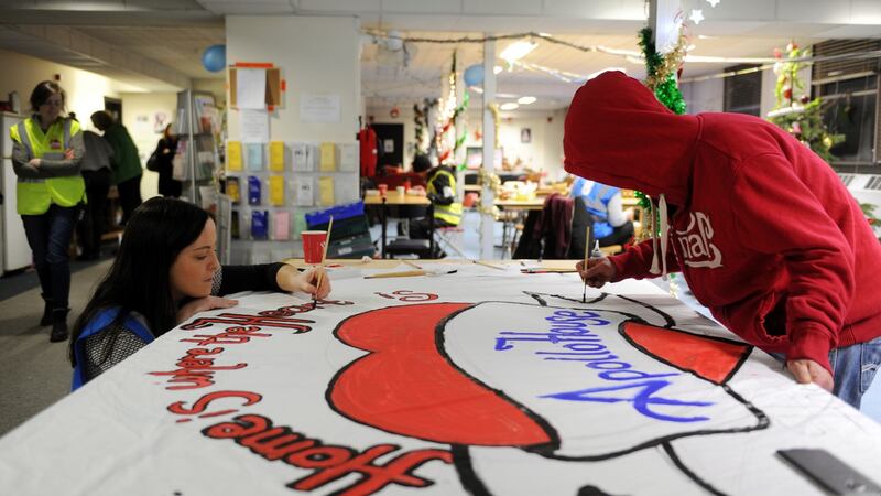 Residents and volunteers pictured painitng a sign inside Apollo House. Photograph: Aidan Crawley/The Irish Times