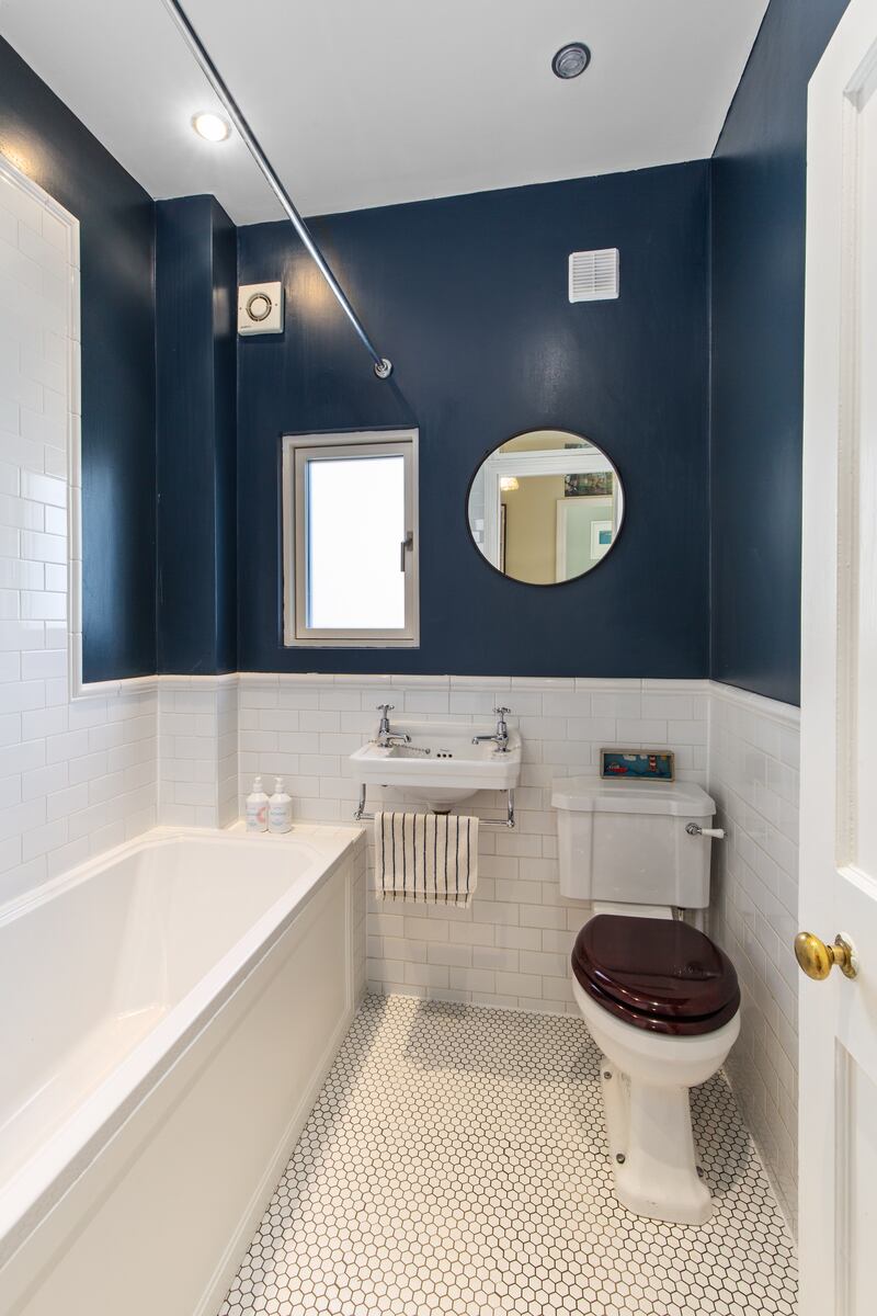 The bathroom, painted dark-blue with white metro tiling on the walls and small hexagonal tiles underfoot. Photograph: Keith Owens