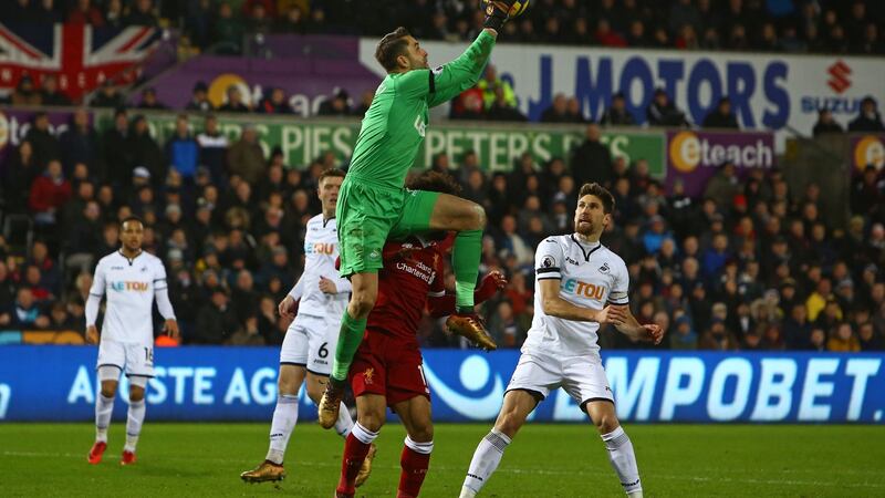 Swansea City goalkeeper Lukasz Fabianski catches the ball over the head of  Liverpool’s  Mohamed Salah. Photograph:   Geoff Caddick/AFP/Getty Images