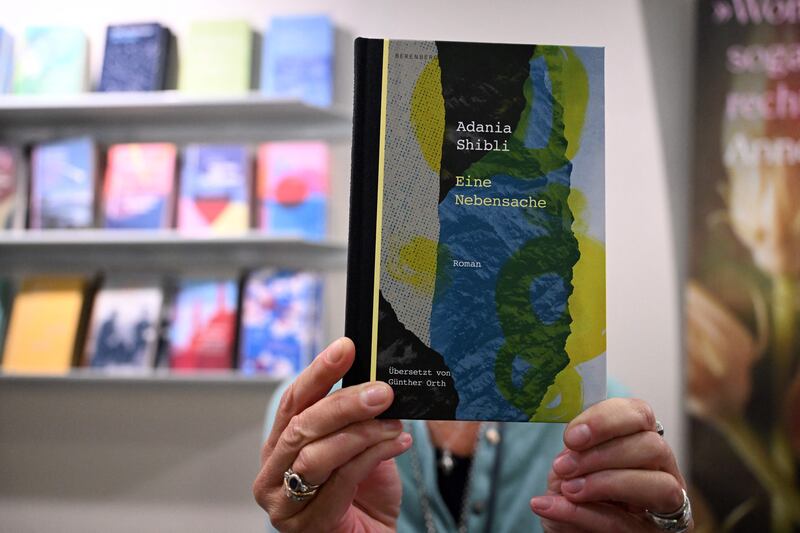 An exhibitor poses with the German edition of the book by Palestinian author Adania Shibli with the title Minor Detail at the Frankfurt Book Fair. The postponement of Palestinian author's award ceremony at the fair due to the Israel-Hamas war triggered condemnation from high-profile authors. Photo by Kirill Kudryavtsev/Getty Images
