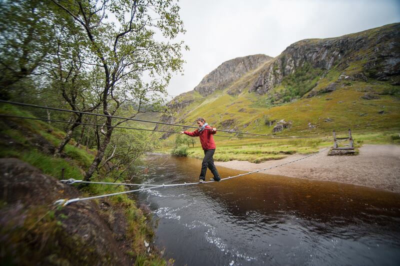 The Steall wire bridge crossing the flowing Allt Coire a'Mhail river at Fort William, Scotland. Photograph: Getty Images