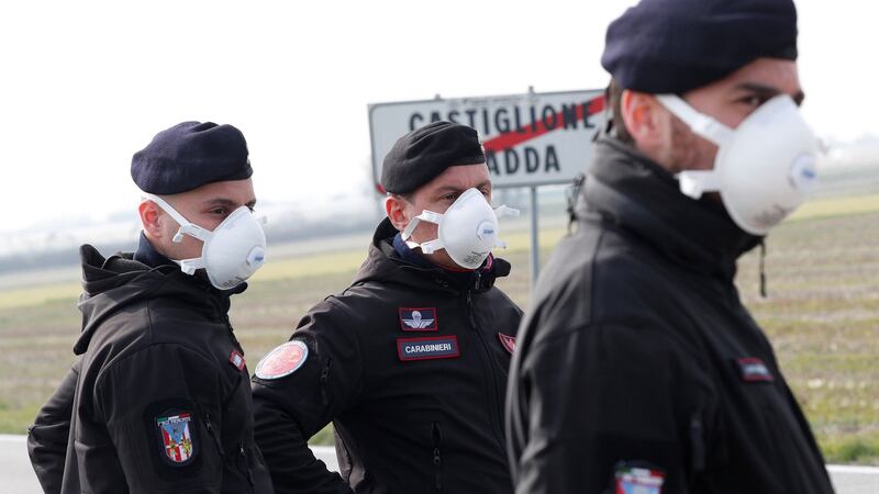 Italian carabinieri officers stand guard outside a town closed by the government due to coronavirus. Photograph: Guglielmo Mangiapane/Reuters