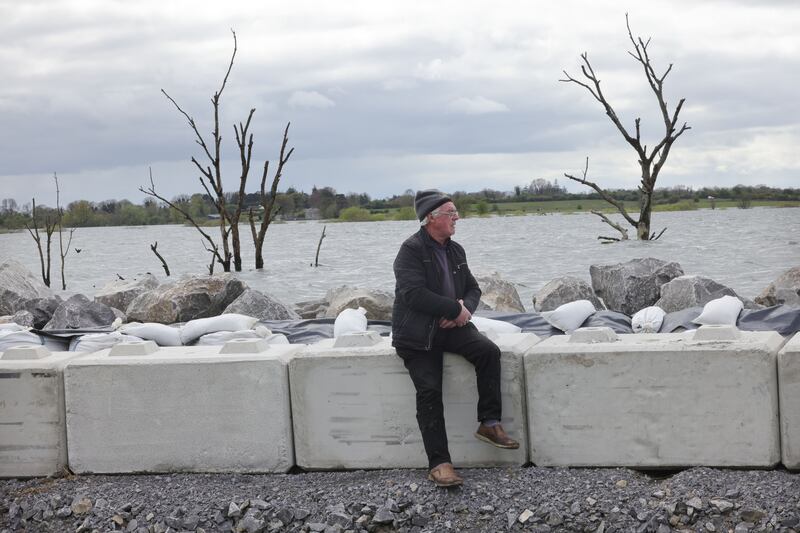 Tommy Carney sits on the barriers which are keeping the rising waters of Lough Funshinagh from entering his home. Photograph: Alan Betson/The Irish Times