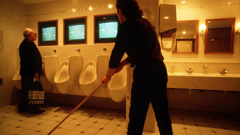 A cleaner and a man using the urinal keep an eye on the match in the Jury’s Hotel. Photo: James Meehan/Inpho