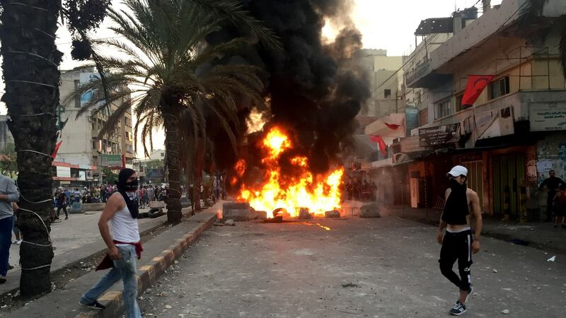 Demonstrators walk near burning tires in Tripoli on Saturday. Photograph: Omar Ibrahim/Reuters