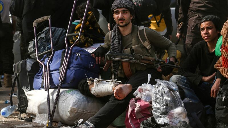 A Syrian rebel fighter sits with a bandaged leg and Kalashnikov next to his crutches in the village of Qalaat al-Madiq. Photograph: Zein al-Rifai/AFP/Getty