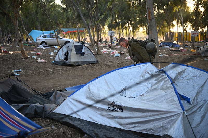 An Israeli soldier searches for IDs and belongings among cars and tents at the Supernova Music Festival site where hundreds were killed and dozens taken hostage by Hamas militants on October 7th, 2023. Photograph: Leon Neal/Getty 