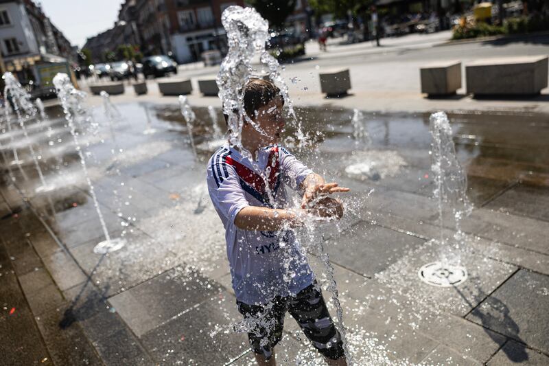 A boy cools off at a fountain in the Place d'Armes in Calais, northern France. Photograph: Sameer Al-Doumy/AFP/Getty