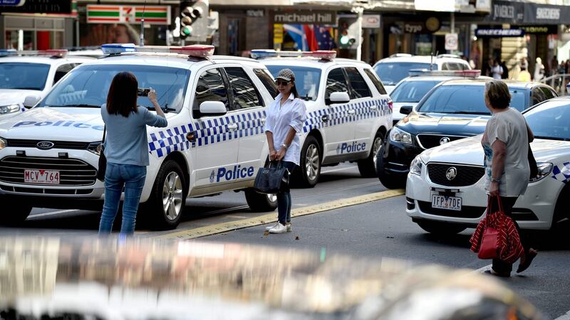 Tourists take photos between police cars after a car ploughed into pedestrians in the centre of Melbourne on Friday. Photograph: Peter Parks/Getty Images