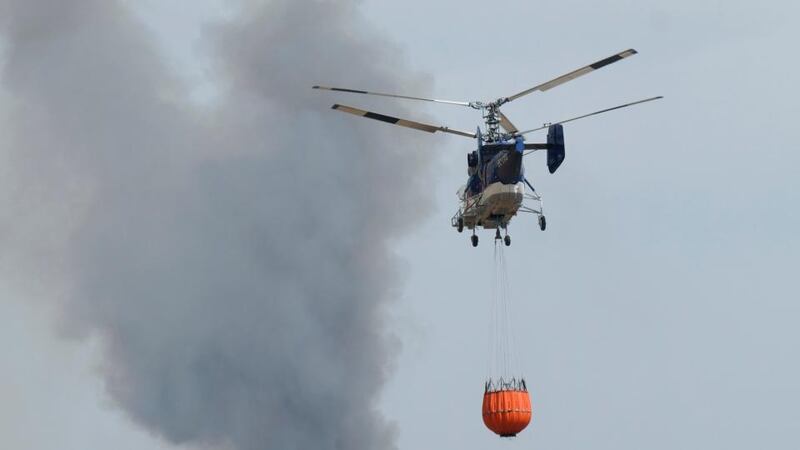 Spanish forest fire: a helicopter carries water to help extinguish burning trees in Huelva province. Photograph: Julian Perez/EPA