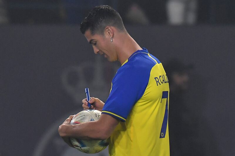 Al-Nassr's new Portuguese forward Cristiano Ronaldo autographs a ball for the fans. Photograph: AFP via Getty