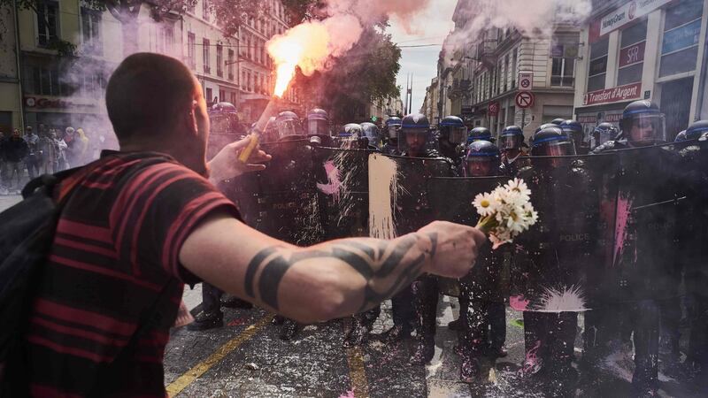 A man holds a bouquet of flowers and a flaming torch as he faces riot police during a demonstration against the government’s planned labour reforms in Lyon, France. Photograph: Jean-Philippe Ksiazek/AFP/Getty Images