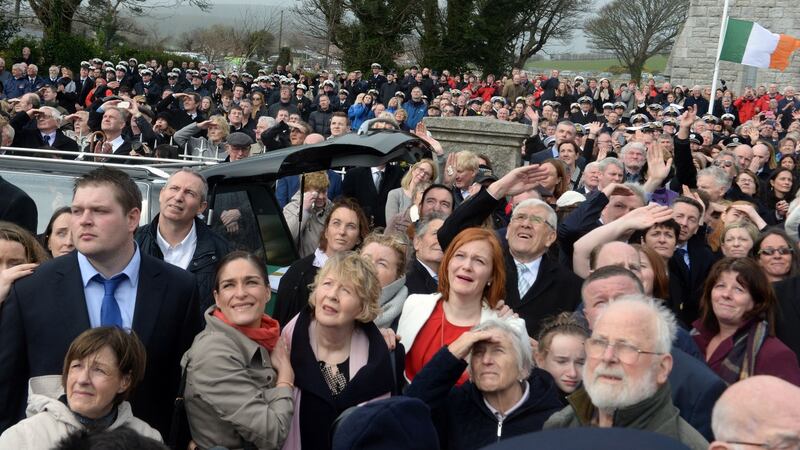 Attendees at the funeral look on as an Irish Coast Guard helicopter performs a flyover at the funeral. Photograph: Cyril Byrne/The Irish Times